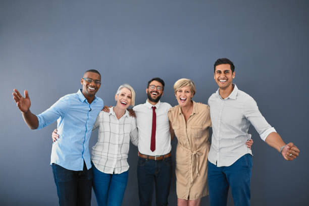 You bet we're the best group you've ever seen! Studio portrait of a diverse group of businesspeople cheering while standing against a grey background cheering group of people success looking at camera stock pictures, royalty-free photos & images
