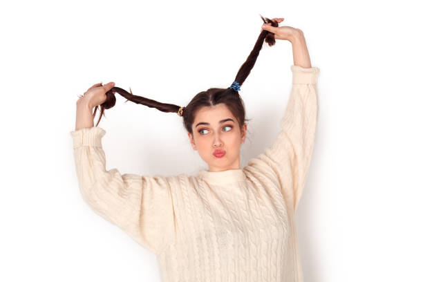 istock Young woman studio standing isolated on white holding ponytails up pouting lips childish 1174453110