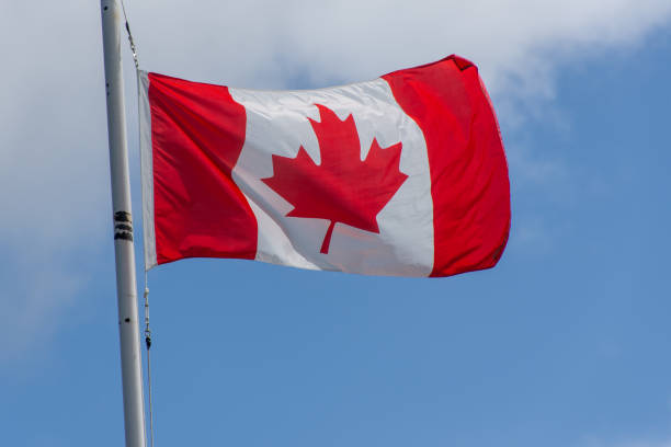 istock Red and White Maple Leaf Canada flag blowing in the wind s on a bright sunny day with blue sky 1174456710