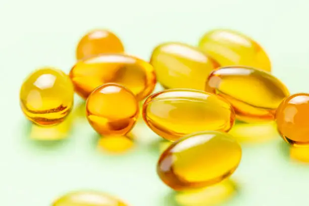 Close up of Vitamin D3 Omega 3 fish oil capsules on green background
