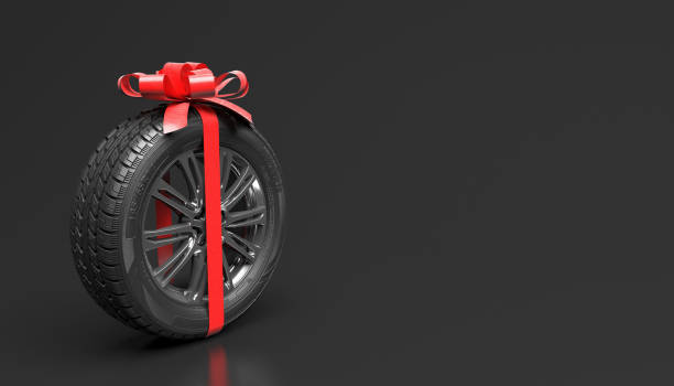 single new car wheel with red bow isolated on a black background. gift or promotional wheel. mock up for advertising of tire fitting or auto maintenance. copy space for text or logo. 3d rendering. - car tire red new imagens e fotografias de stock
