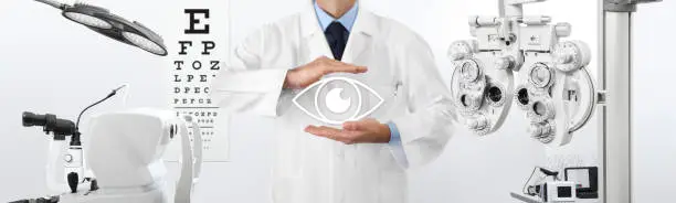Photo of concept of eye examination, optician hands protecting an eye icon, prevention and control, on background tools for diagnostics, web banner