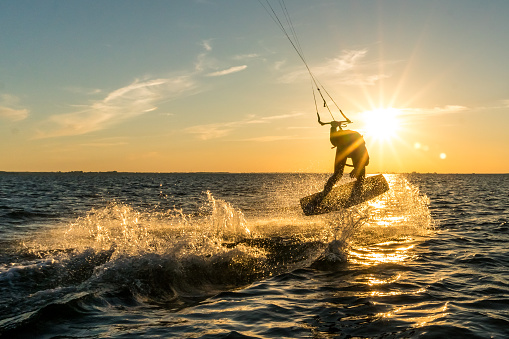kitesurfer doing tricks in sunset