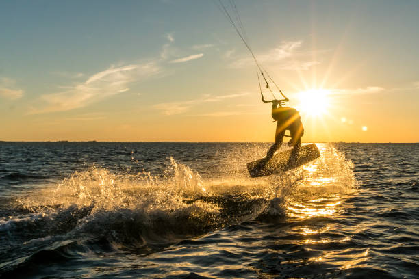 kitesurfer doing tricks in sunset kitesurfer doing tricks in sunset kiteboarding stock pictures, royalty-free photos & images