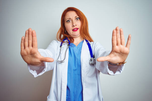 istock Young redhead doctor woman using stethoscope over white isolated background doing stop gesture with hands palms, angry and frustration expression 1174467244