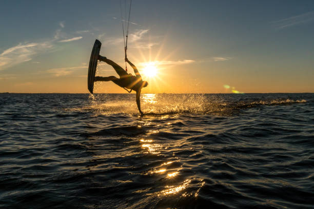 istock kitesurfer doing handslide in sunset with sunstar and beautiful silhouette 1174467251