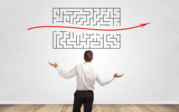 istock Businessman looking to a maze on a wall 1174467500