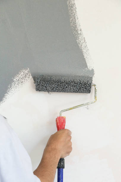 istock Paint roller. Painting with gray paint over a white wall 1174467629