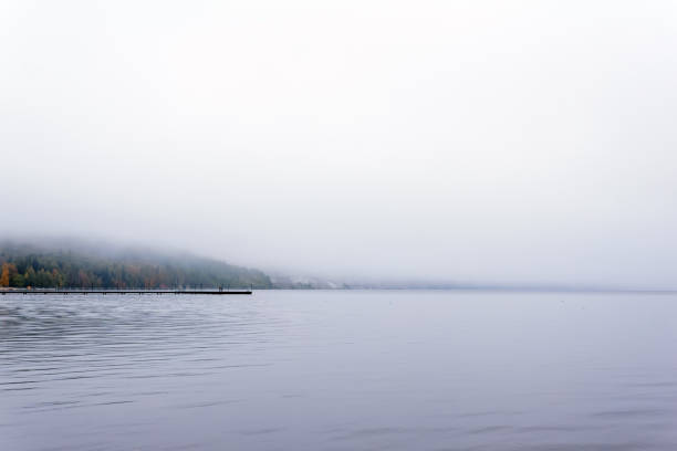 morning waterscape - a mountain lake hidden by fog, with a distant pier