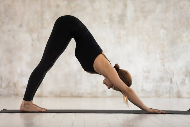 istock Woman doing downward-facing dog pose yoga exercise indoors 1174472414