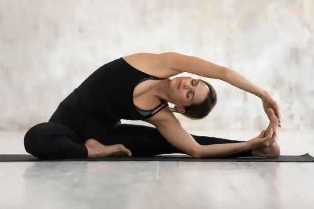 Photo of Woman doing Revolved Head to Knee Forward exercise indoors