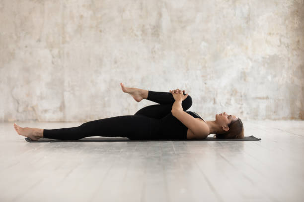 胸のポーズに半膝をやってマットの上に横たわっている女性 - stretching yoga exercise mat women ストックフォトと画像