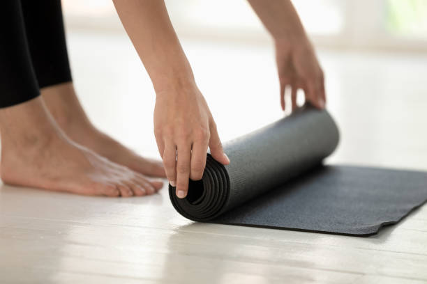 istock Sportswoman rolling black mat before or after yoga session 1174472528