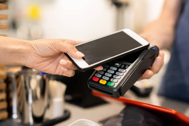 istock Young woman using her mobile phone for contactless payment while visiting cafe 1174473385