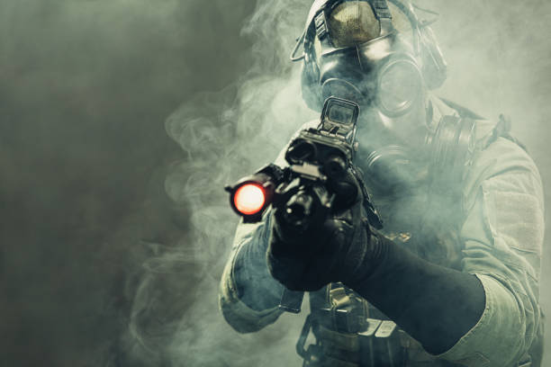 istock Special force soldier with gasmask between smoke at battlefield is aiming the target 1174476334
