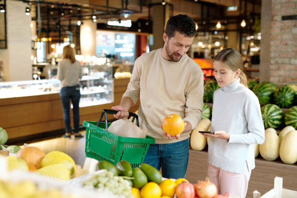 istock Young father with basket consulting with daughter while both choosing ripe melon 1174478318