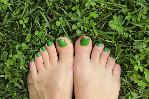 Green pedicure for women's short nails.Nail design in nature colors.