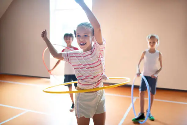 Photo of Girl wearing striped t-shirt smiling while rolling hula-hoop