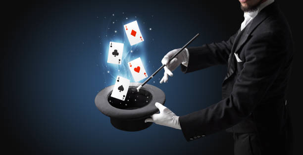 istock Magician making trick with wand and playing cards 1174481363