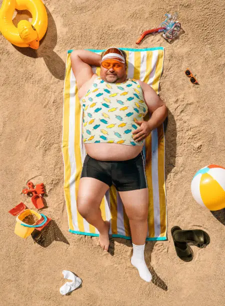 Photo of Funny overweight tourist resting on the beach