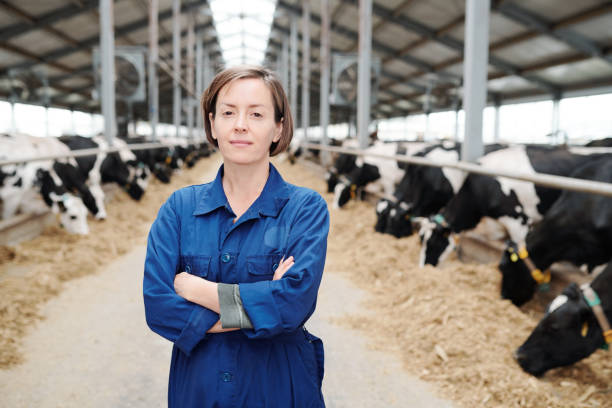 junge selbstbewusste landwirtin oder arbeiterin des bauernhauses, die arme auf der brust kreuzt - bäuerin stock-fotos und bilder