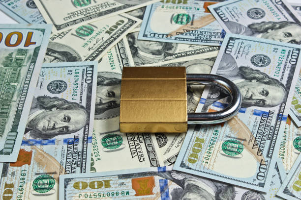 istock Golden lock with key on background of dollar bills 1174490482