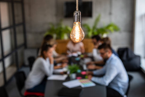 Young creative business people meeting at office. Young business people are discussing together a new startup project. A glowing light bulb as a new idea. new idea office stock pictures, royalty-free photos & images