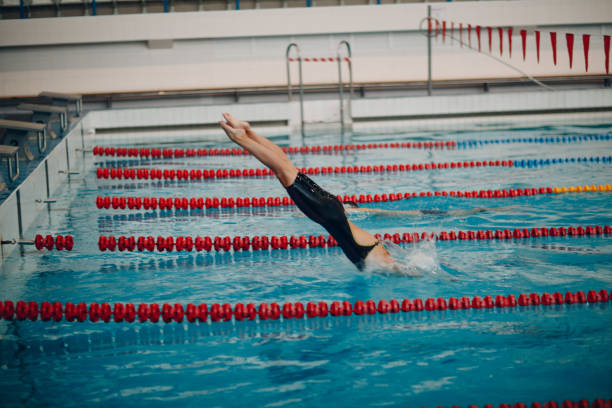 istock Young woman swimmer jumping in swimming pool 1174491475