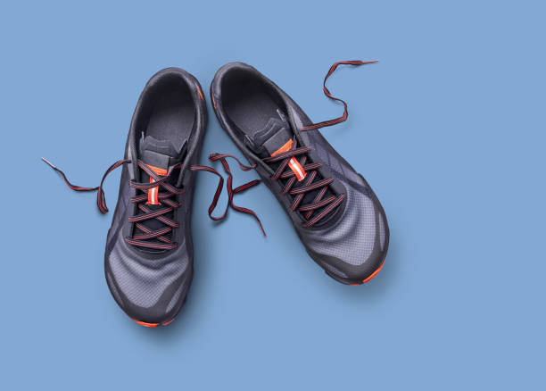 istock Gray and orange trainers isolated on a blue background. 1174497025