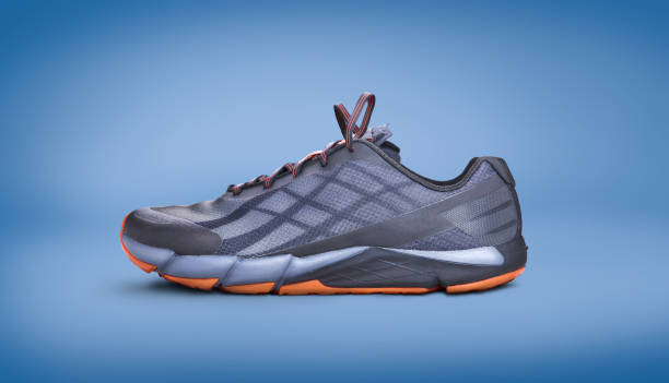 istock Gray and orange trainers isolated on a blue background. 1174497251