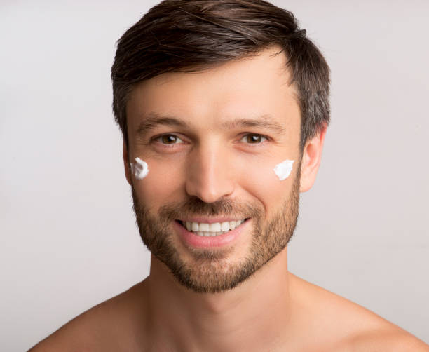 istock Man Applying Anti-Aging Cream On Face Over White Background 1174502441