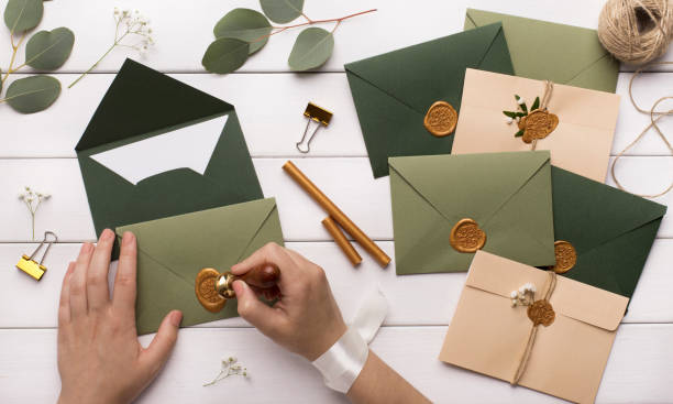 Woman preparing invitations for wedding on white wooden table