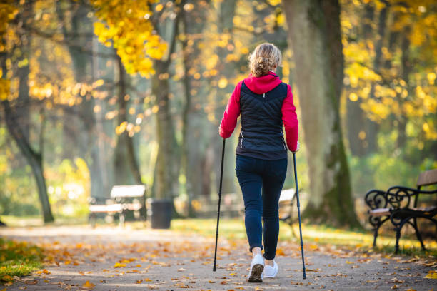 mid aged woman nordic walking im stadtpark - power walken stock-fotos und bilder