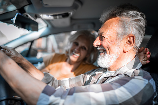 Smiling senior couple enjoying a car ride.road trip, travel and old people concept - happy senior couple driving in car