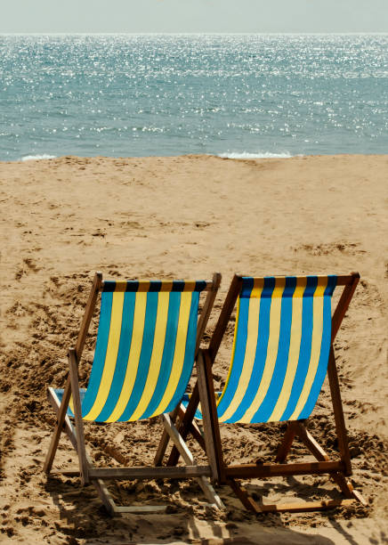 istock Two Deckchairs on a sandy Beach by the Sea 1174511261