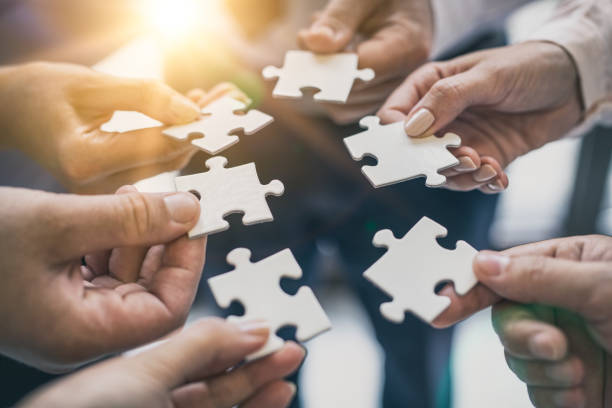 istock A group of business people assembling jigsaw puzzle. 1174513070