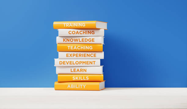 books of  training and development in front of blue wall - success practicing book stack imagens e fotografias de stock