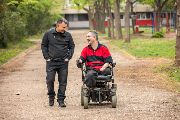 disabled person in electric wheelchair in a public park with a friend - power supply power supply box power equipment imagens e fotografias de stock