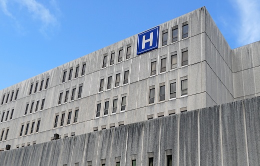 Large grey concrete building with H sign for hospital