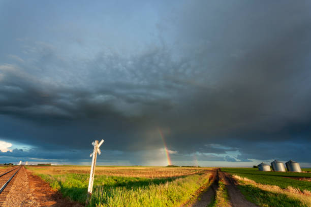 Out following storms, Saskatchewan, Canada. Lone dirt road leading to grain elevators,  Image taken from a tripod.
