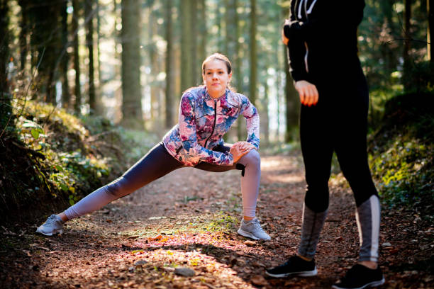 istock Young Women Warming Up And Stretching Before Running in Forest 1174527468