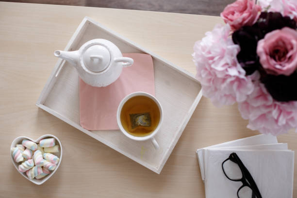 Directly above shot of tea, foam candies, flower arrangement and books on coffee table in.