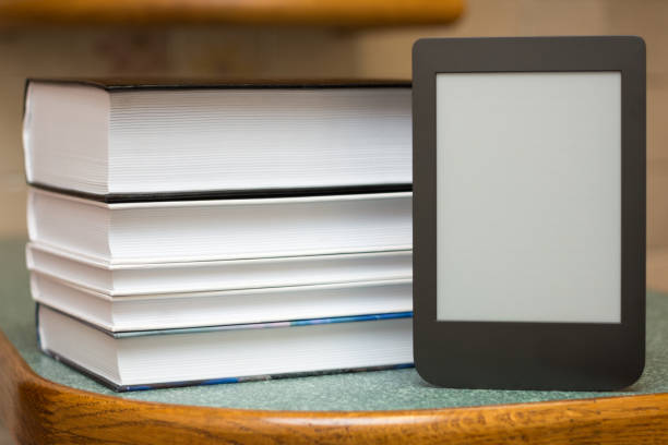 istock Modern e-book on the background of a stack of thick paper books. Close-up with selective focus. Training and technology concept 1174533873