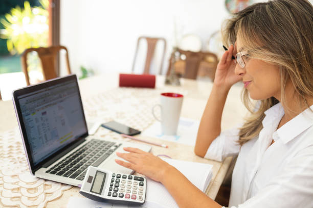 istock Modern woman using laptop, cell phone and calculator 1174534699