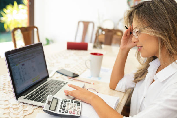 istock Modern woman using laptop, cell phone and calculator 1174534810
