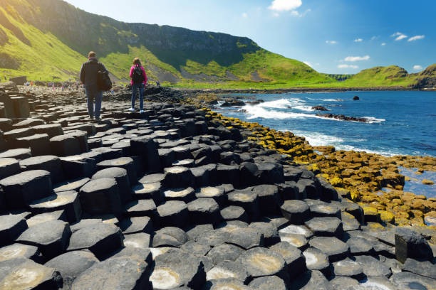 Two tourists walking at Giants Causeway, an area of hexagonal basalt stones, County Antrim, Northern Ireland. Famous tourist attraction, UNESCO World Heritage Site. stock photo