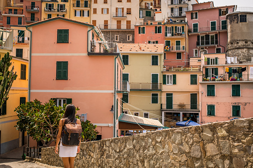 Female tourist relaxing by the sea. She is looking at the beautiful town Riomaggiore, Cinque Terre
