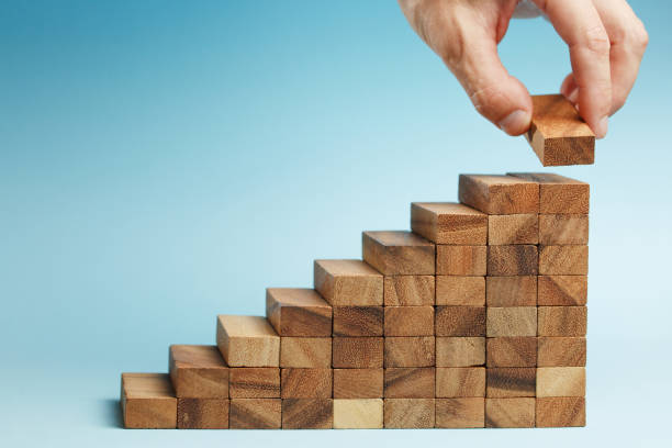 istock hand put wooden blocks arranging stacking for development as step stair 1174541628