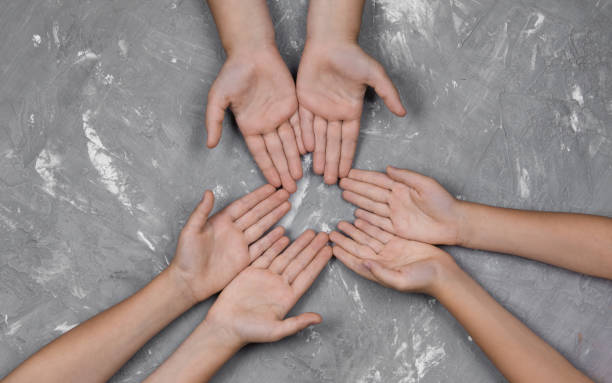 istock children's hands together in a circle on gray background, top view. 1174541729