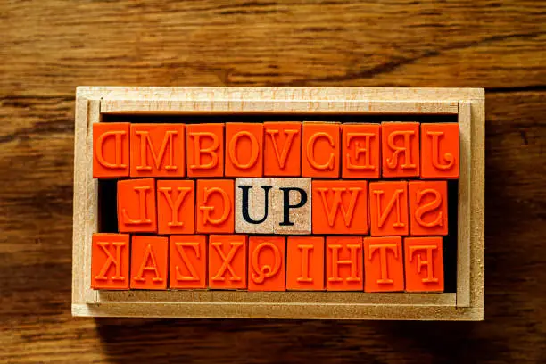 Photo of UP - isolated abstract in wood type stamps against wooden background and copy space.